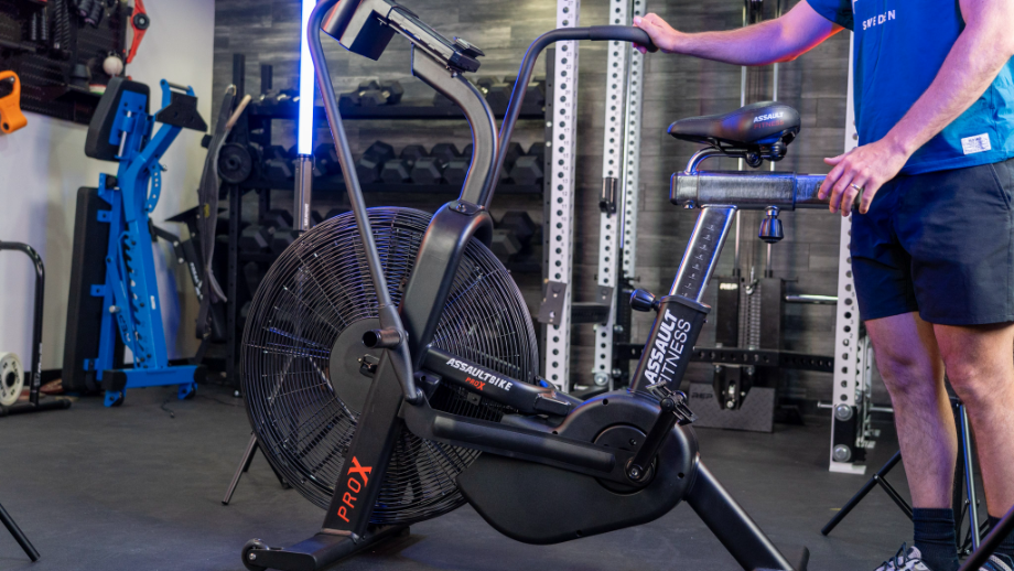 Full shot of AssaultBike ProX with man standing next to it