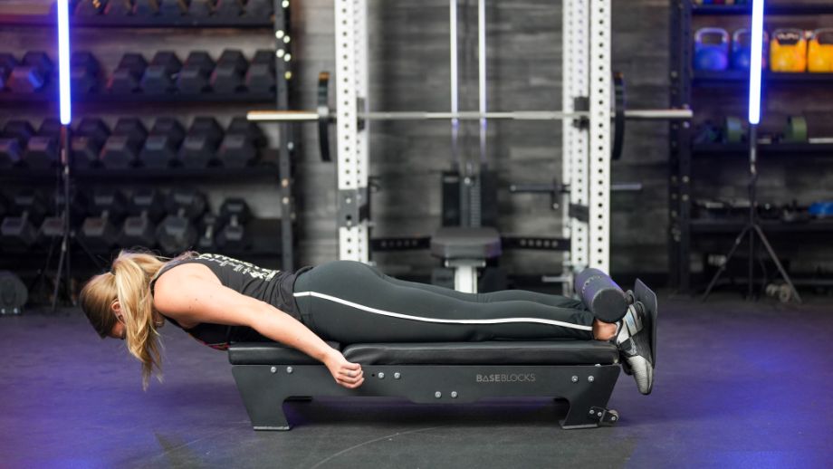 Woman with legs fully extended during a Nordic hamstring curl on the BaseBlocks Nordic Plus
