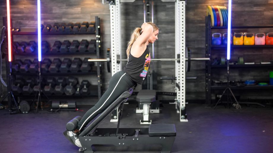 Woman with hands behind her head at the top of hyperextension on the BaseBlocks Nordic Plus