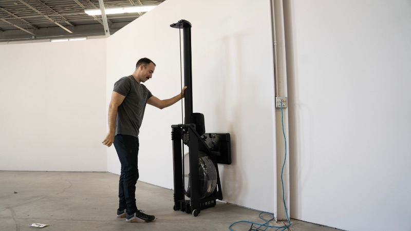 man standing up a water rowing machine vertically