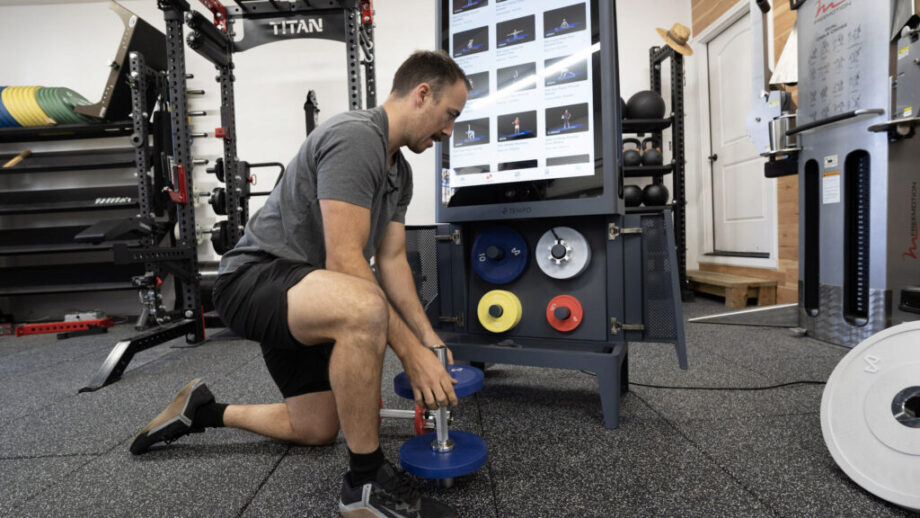 Coop loading a dumbbell handle to prepare for a workout with Tempo Studio - Tempo Studio review-tempo discount code