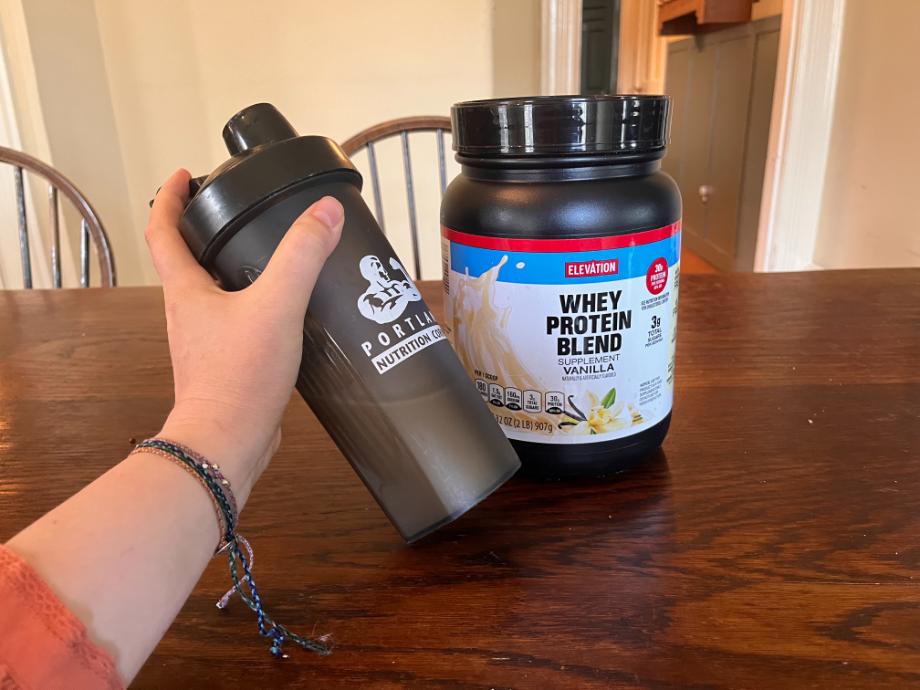 Shaker cup in front of Elevation protein powder canister