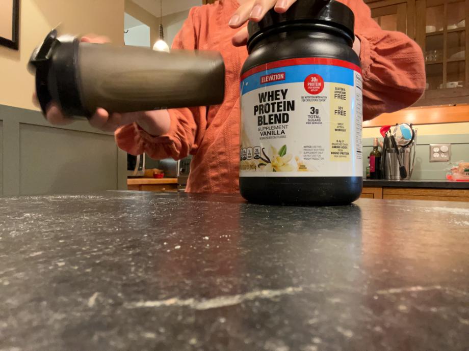 Woman making a Elevation protein powder drink in a shaker bottle