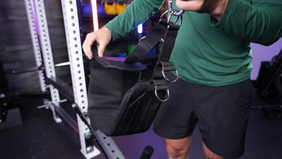 Man holding up the belt for the Fringe Sport Belt Squat attachment