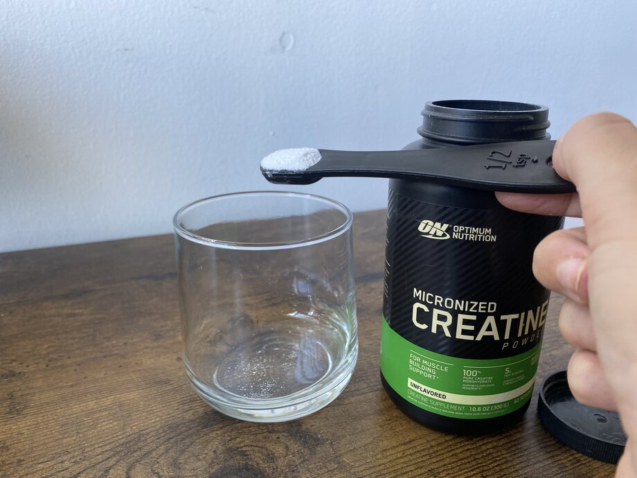 Scooping Optimum Nutrition Creatine into a glass
