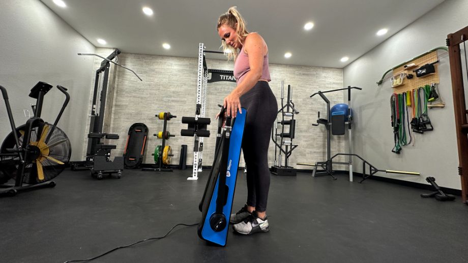 Woman standing with folded LifePro PacerMini treadmill in an upright position