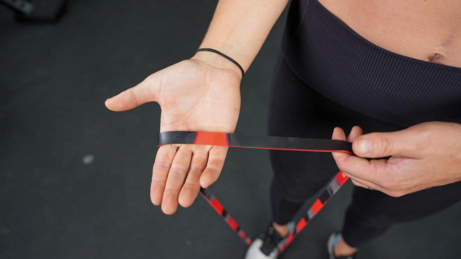 Hands hold out and display the Red Living.Fit Camo Band