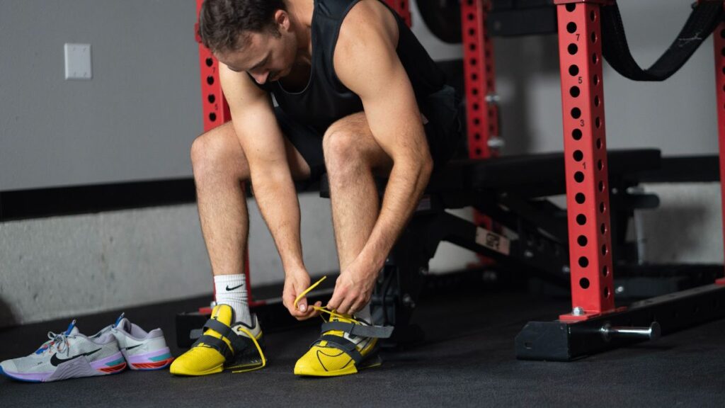 Man tying the laces on yellow and black Nike Romaleos weightlifting shoes