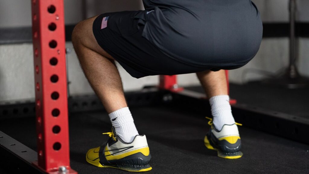 A man squatting in the Nike Romaleos 4 weightlifting shoes during squats in a red squat rack