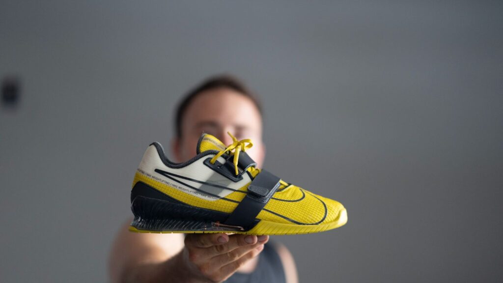 Man holding Nike Romaleos 4 weightlifting shoes to show side profile against a gray background