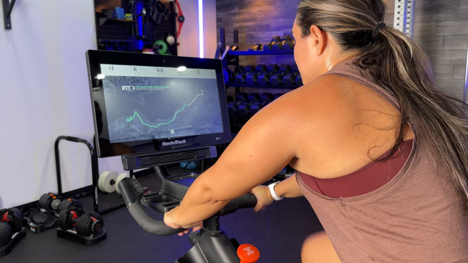 woman riding NordicTrack S22i exercise bike with virtual course on the screen
