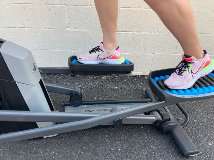 Caroline showing the NordicTrack Commercial 14.9 in use. She is wearing pink Nike shoes. The elliptical has blue pedals.
