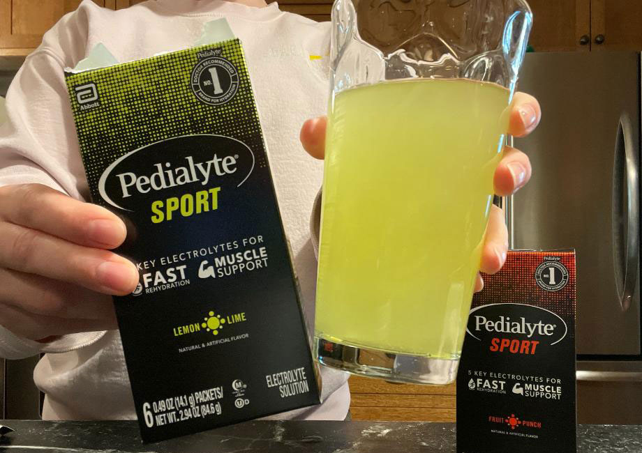 Hands holding out a box and glass of Pedialyte Sport.