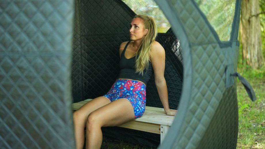 Photo outside SweatTent showing woman sitting on a bench inside the tent