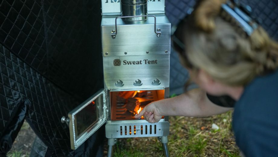 Close up photo of woman starting a fire in the SweatTent