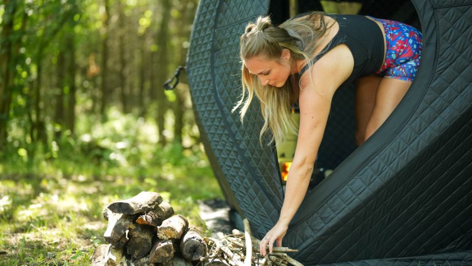 Woman reaching for firewood from the SweatTent