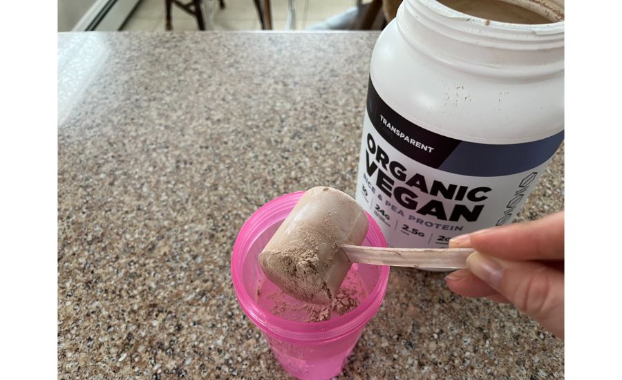 Person scooping Transparent labs Vegan Protein 1 into shaker bottle