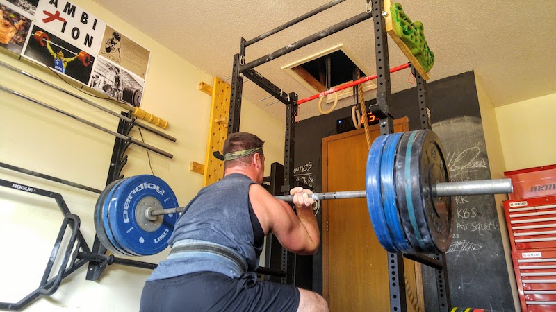 man using a squat rack and performing front squats
