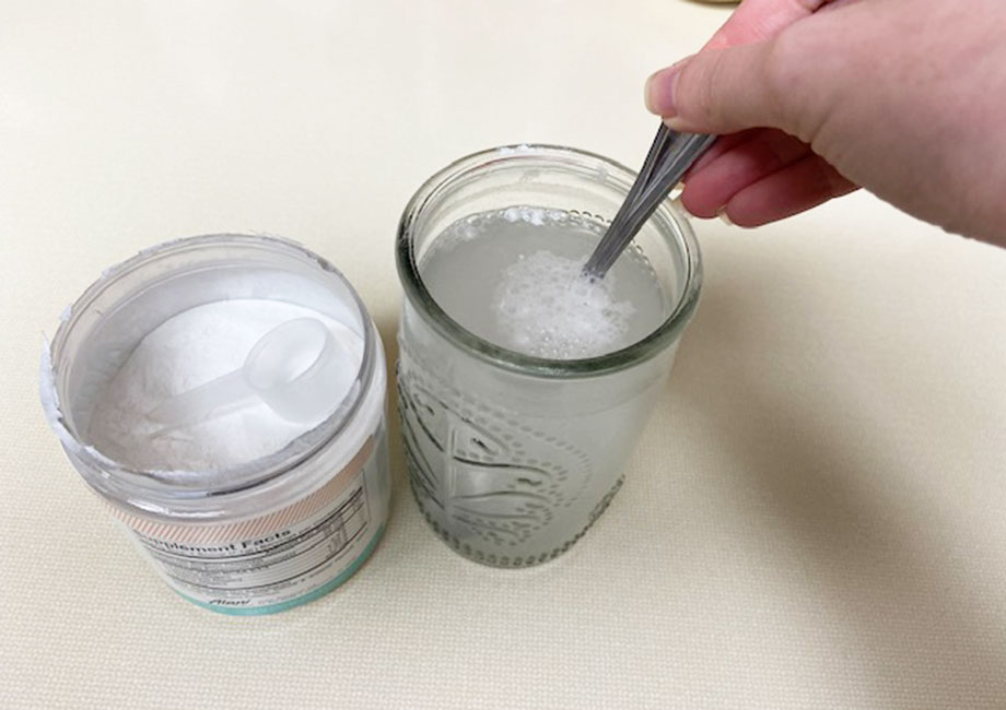 A hand is shown mixing Alani Nu BCAAs in a glass.