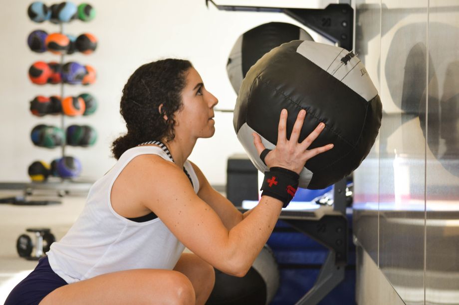 A woman holding a medicine ball during a set of wall ball squats