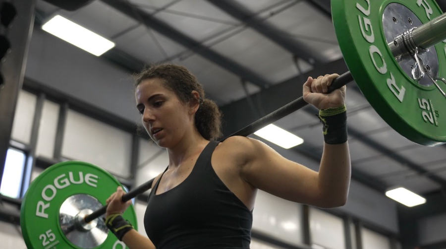 Woman with barbell on back rack in a gym how much does a barbell weigh