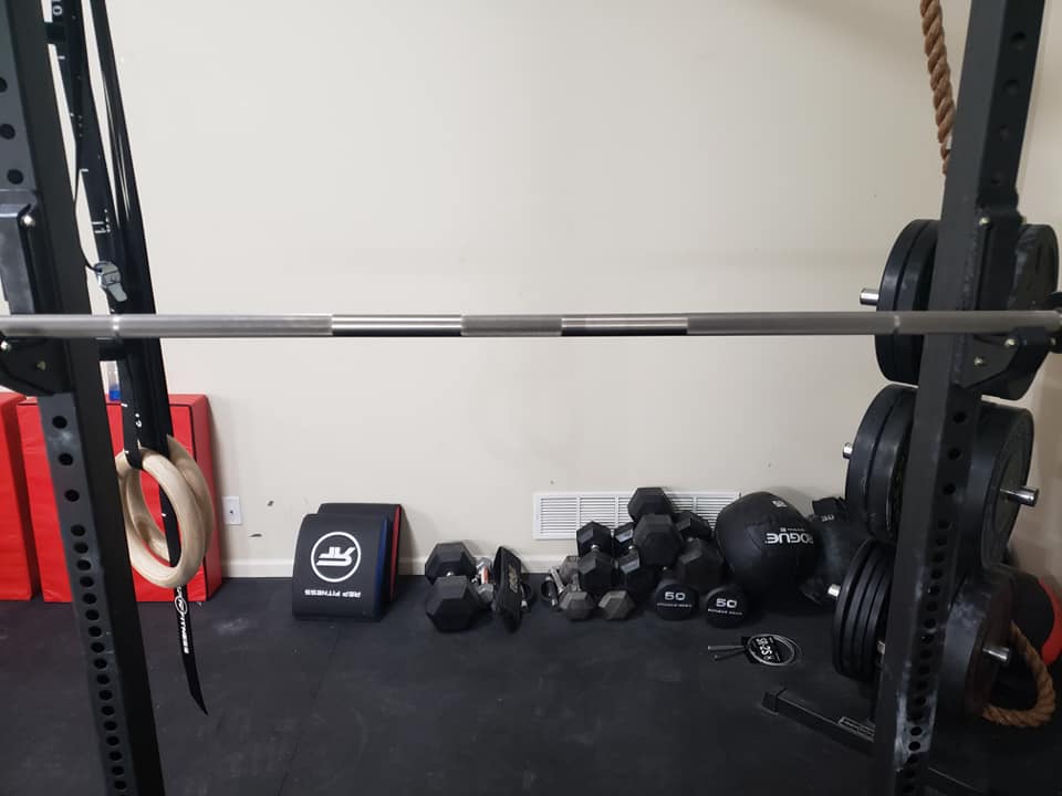 Rogue Pyrros Bar on a squat rack in a garage gym