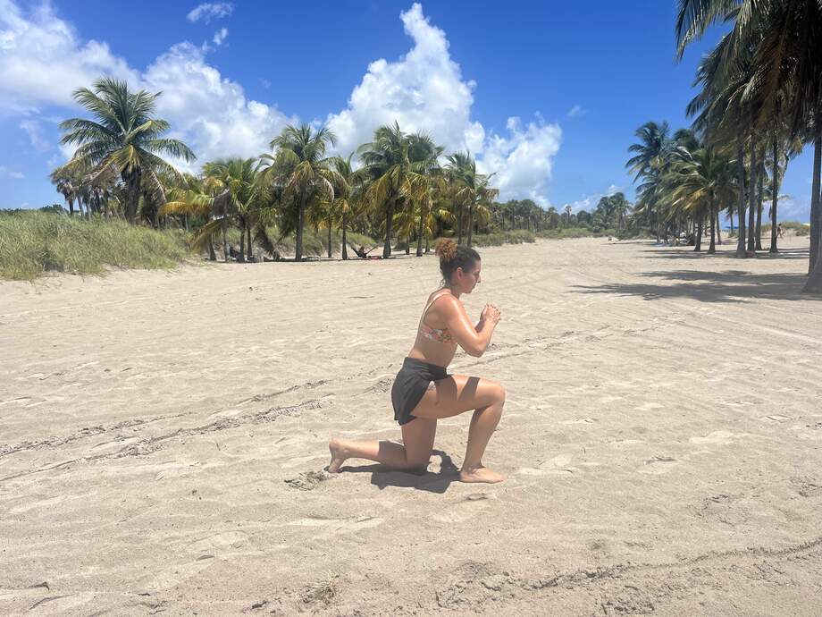 a woman doing lunges on a beach