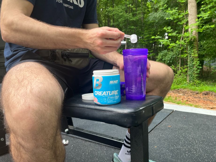 Man scooping Beast Creatine into a shaker cup