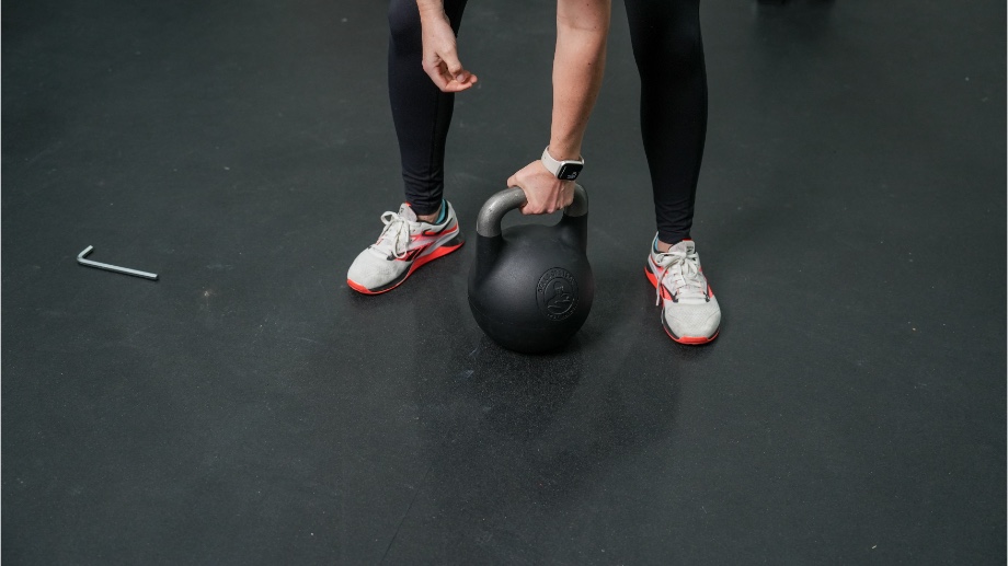 A close look at someone getting ready to lift a Bells of Steel Adjustable Kettlebell with one hand.
