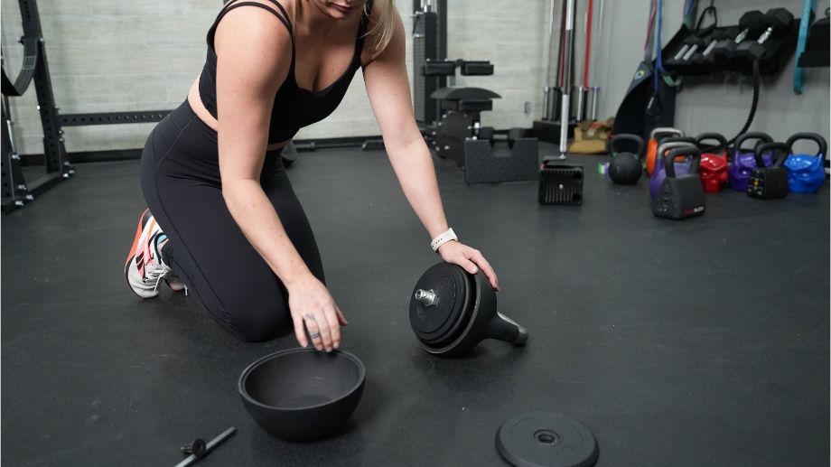 A woman is adjusting the weight plates inside a Bells of Steel Adjustable Kettlebell.
