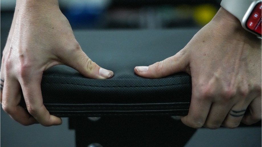 Hands push to show deflection on the padding of a Bells of Steel Flat Utility Bench