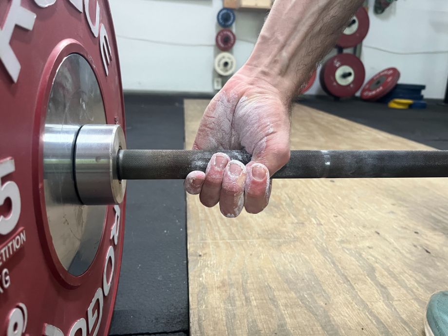 Hand gripping the barbell with chalk