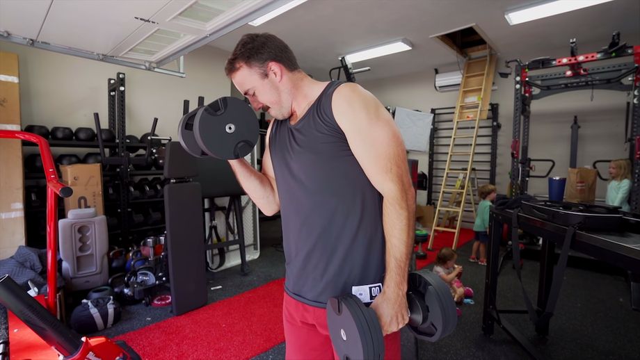 Coop doing dumbbell curls in a home gym