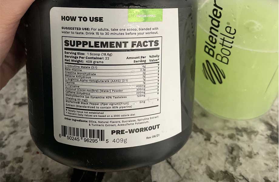 A hand holds up a container of BlackWolf Pre-Workout so the Supplement Facts label can be seen.