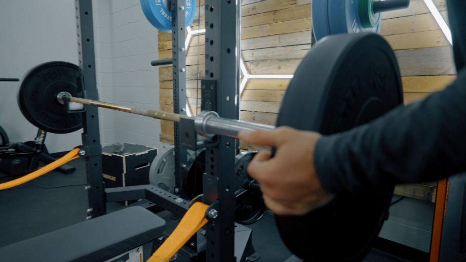 Man loading weight onto a barbell on the Bells of Steel Hydra rack