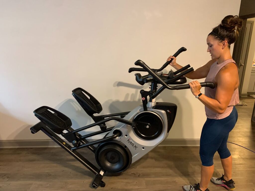 Woman moving the Bowflex Max Trainer M6 around her apartment