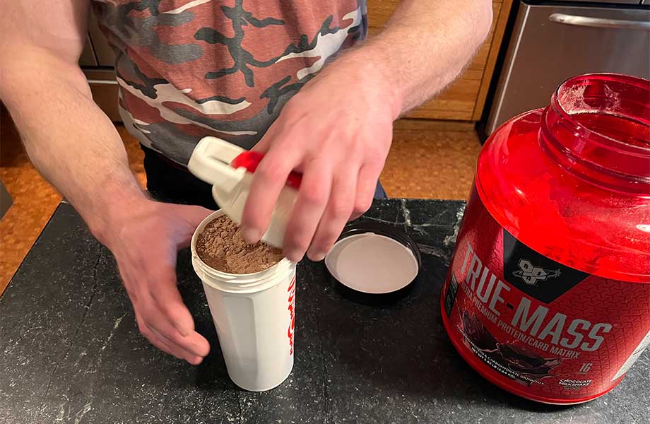 Man closing a shaker cup full of BSN True Mass