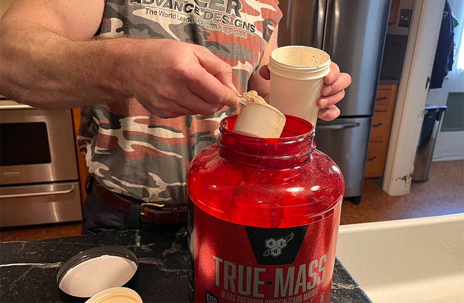 Man scooping BSN True Mass into a shaker cup