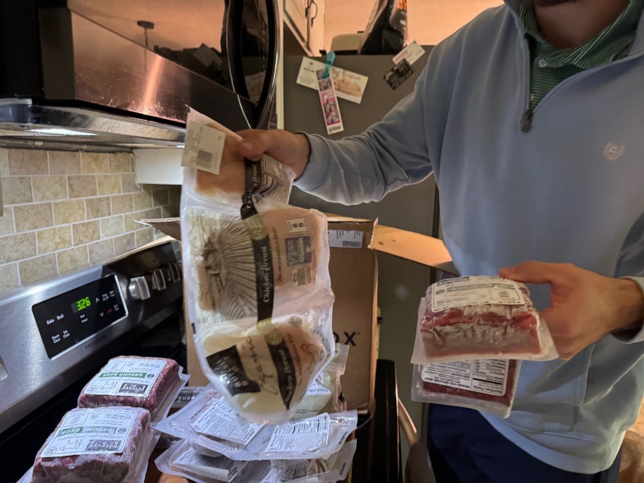 A person holds up frozen packages of chicken and beef from the ButcherBox delivery service.