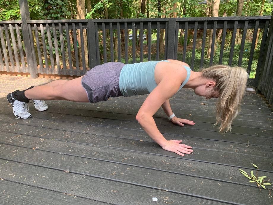 A woman performing a plank outdoors on a deck