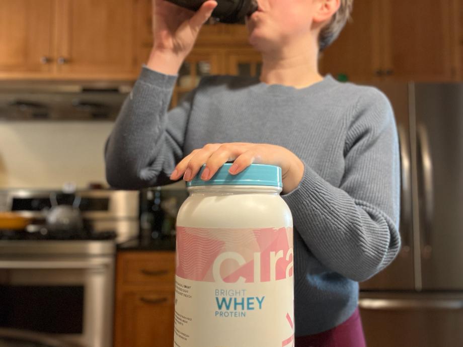 A woman is shown drinking a shake of Cira Bright Whey Protein.