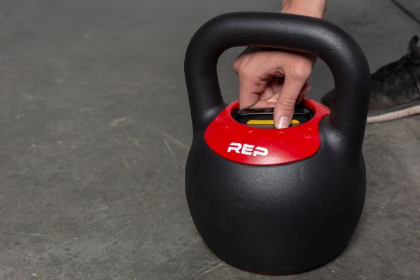 Up close photo of REP Fitness Adjustable Kettlebell featuring a hand on the adjustment mechanism.