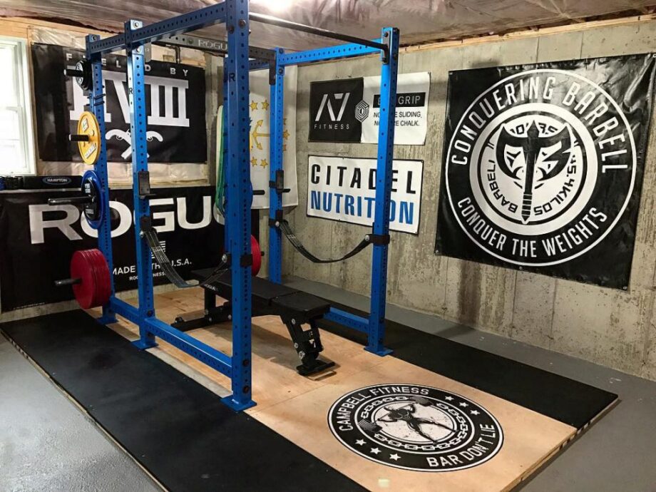 Home gym with a double squat rack and wooden platform.