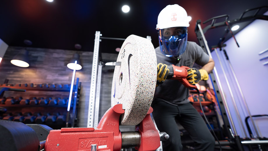 An image of Coop Mitchell from GGR cutting into a Nike bumper plate with a chainsaw