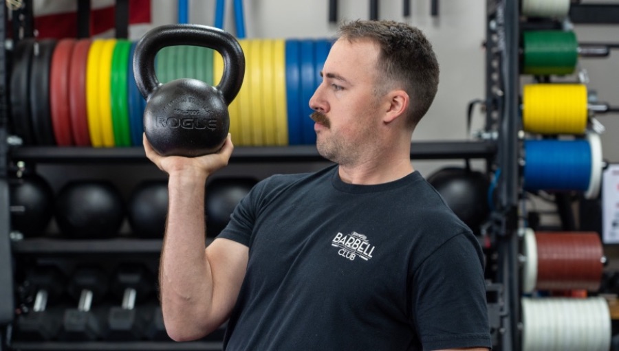 Man holding a kettlebell in a gym