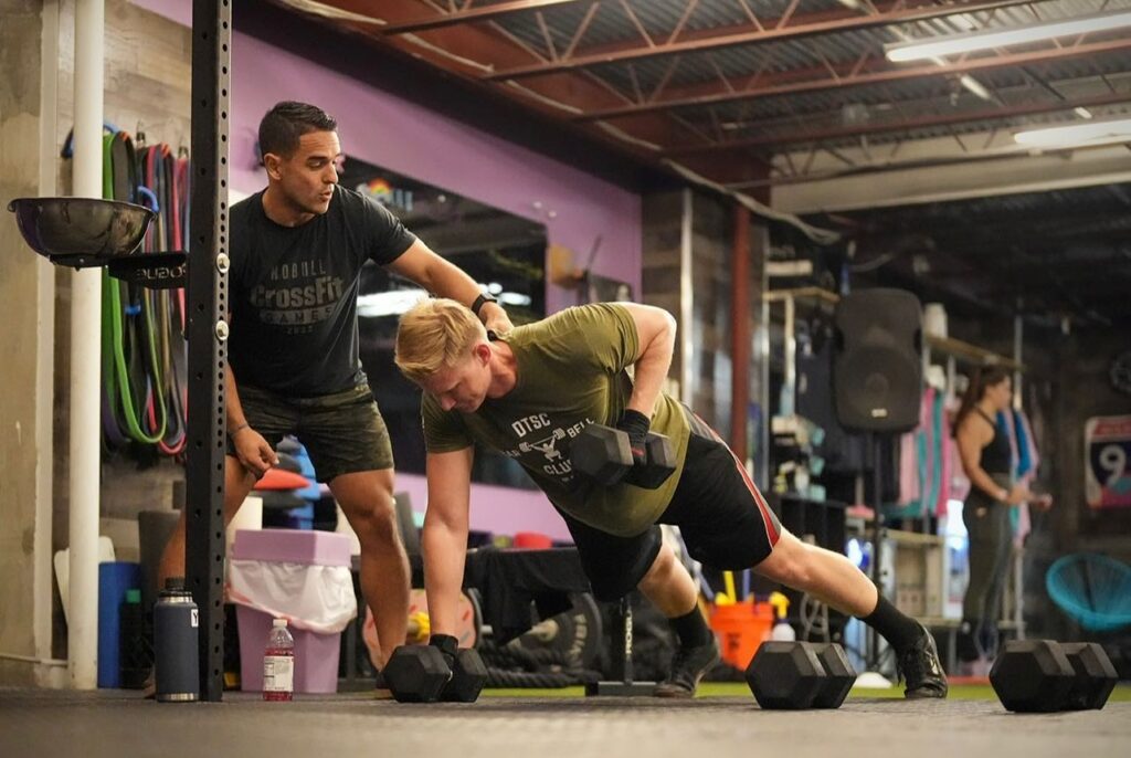 A coach supervises a crossfit trainer