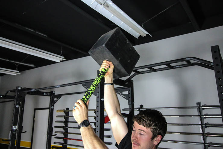 man using the BAMF Hammer in a garage gym