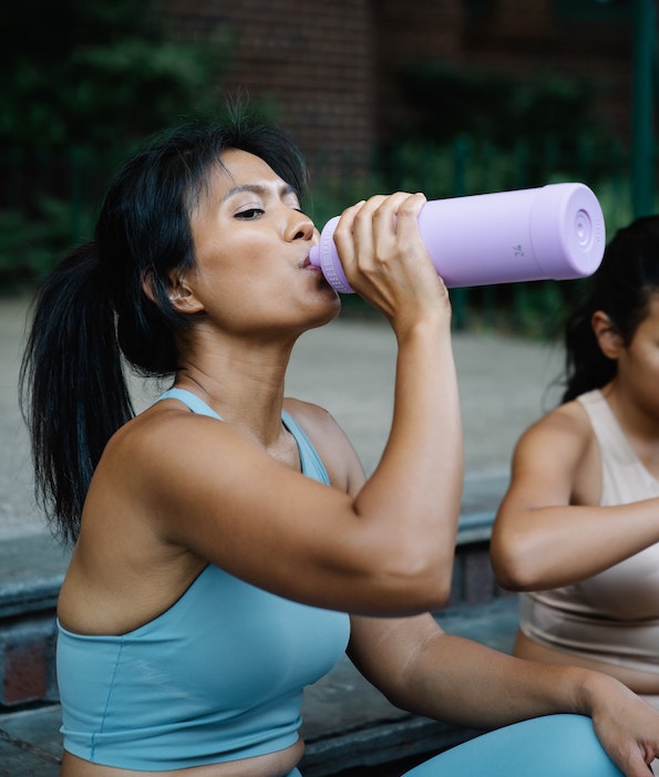 An image of a woman drinking water after a run