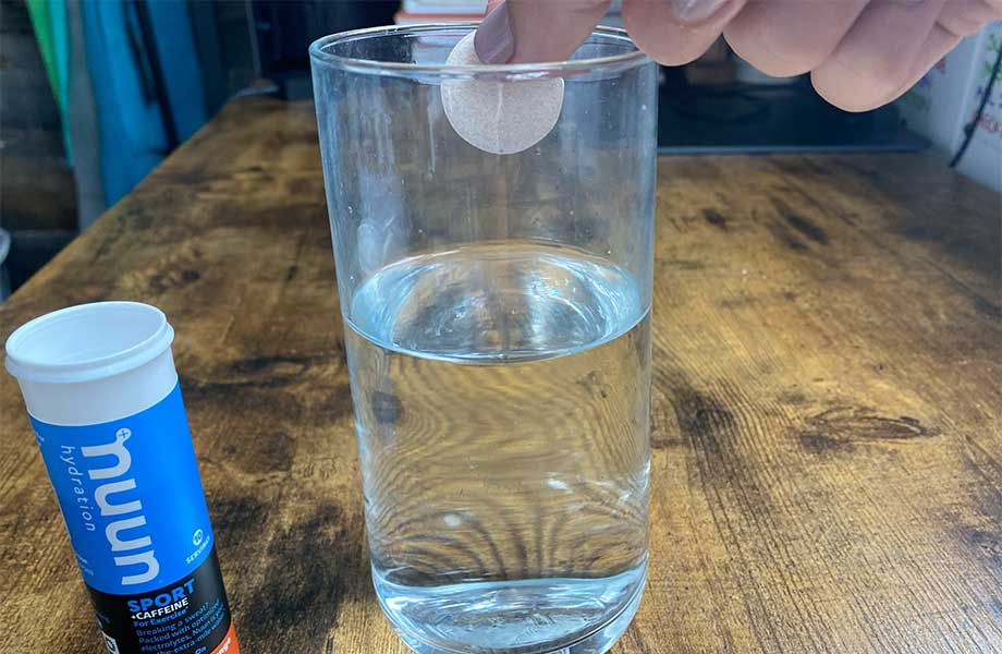 Someone dropping a Nuun Sport electrolyte tablet into a glass