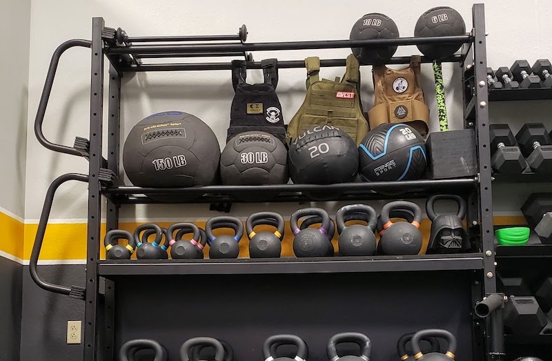 Several weighted vests hanging on a rack in a gym